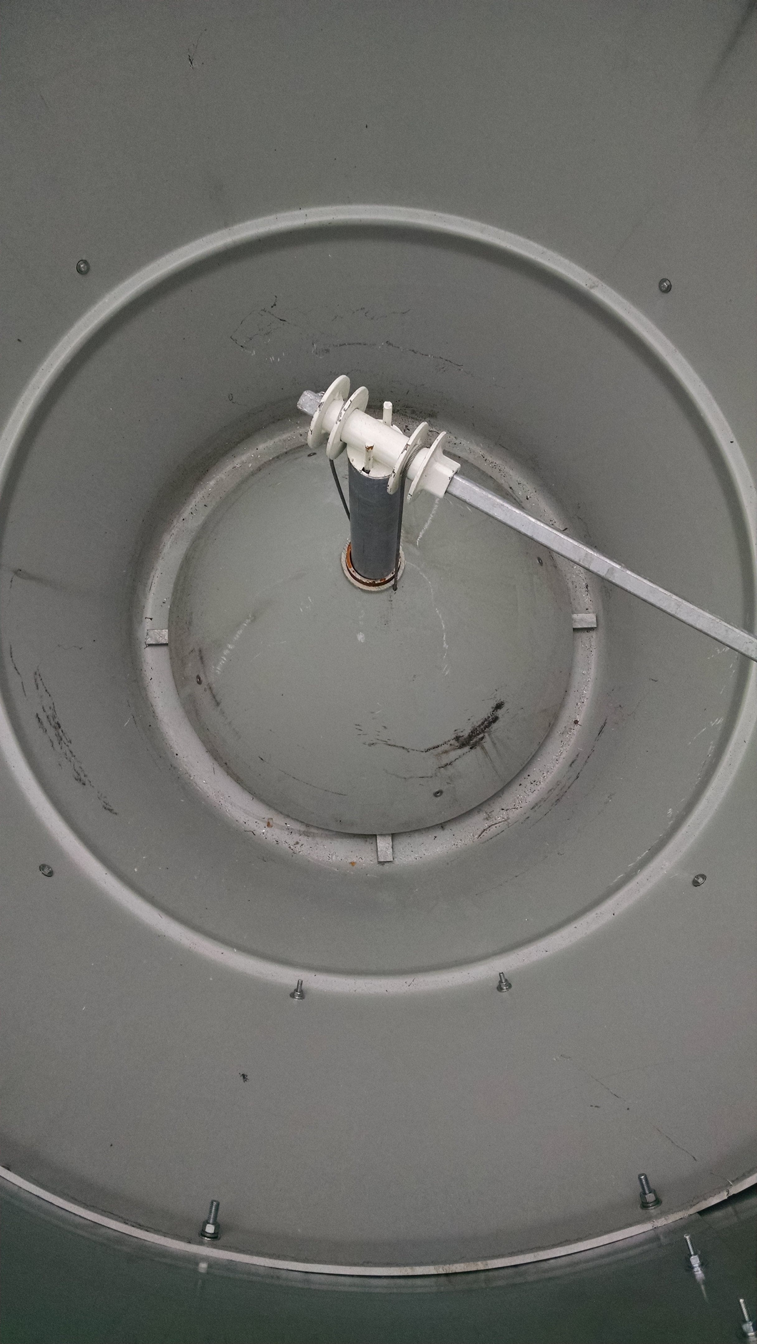 Looking down from the top. The outer wall tapers in toward the bottom and an inner cone in the center directs feed to a spinning agitator just below. The inner cone is raised by cables to adjust the gap to control the flow of feed.