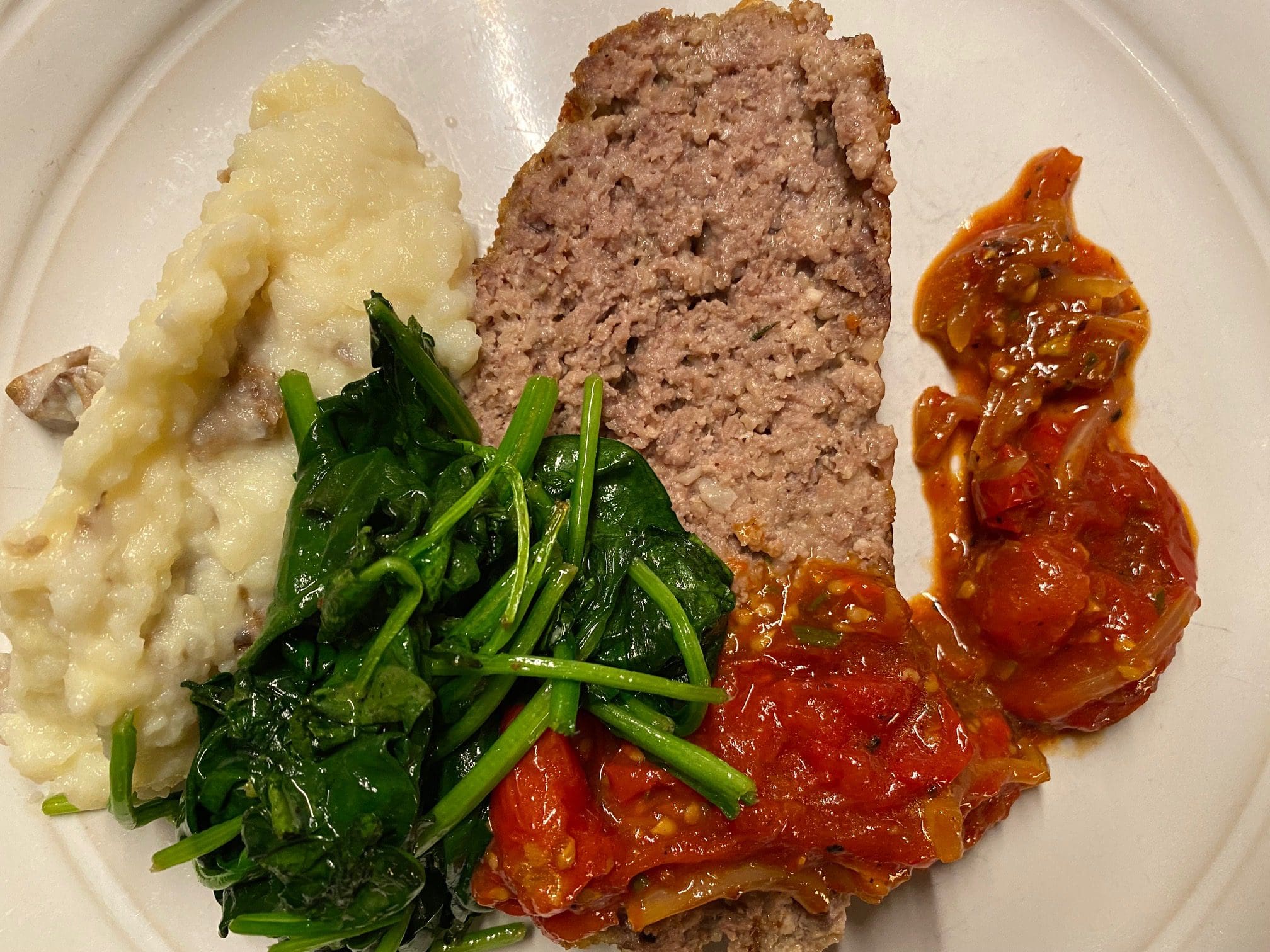 Grass fed beef meatloaf with tomato relish on a plate.