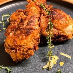 Fried pasture raised and certified organic chicken drumsticks from Wrong Direction Farm served on ceramic plate.