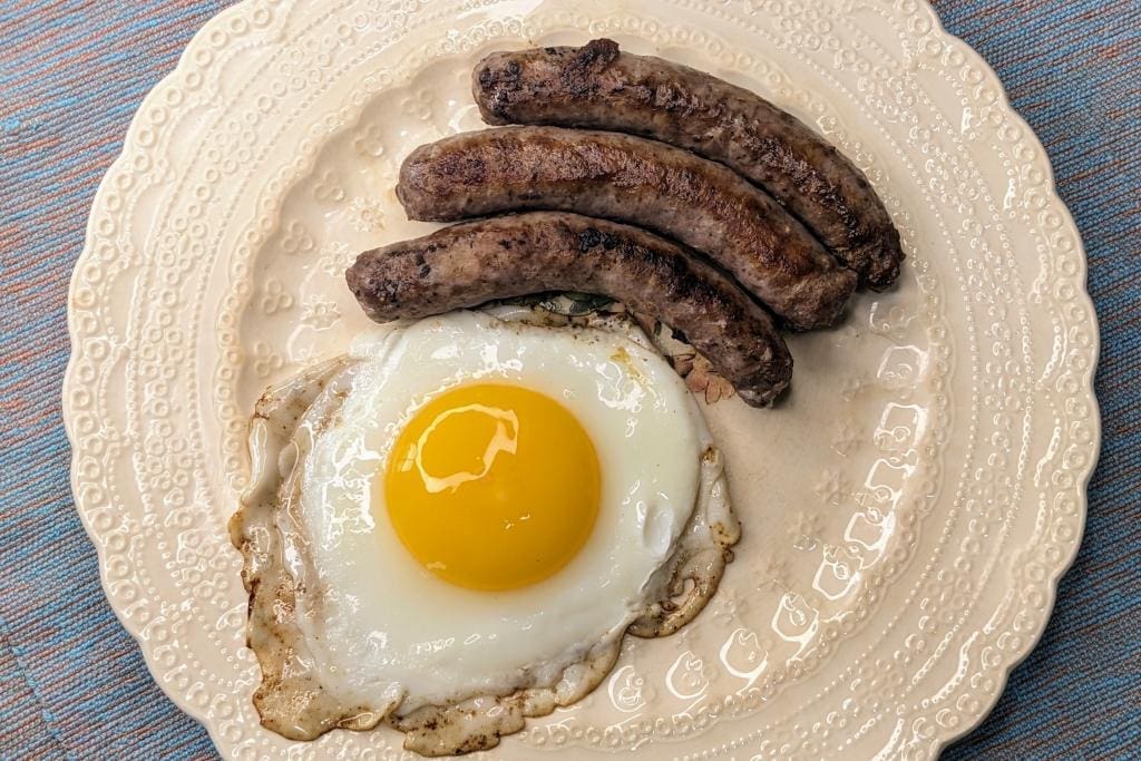 Grass fed beef breakfast sausage links on a plate with a sunny side up egg.