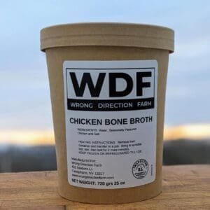 One container of Wrong Direction Farm bone broth on a cutting board with a sunrise sky in the background.