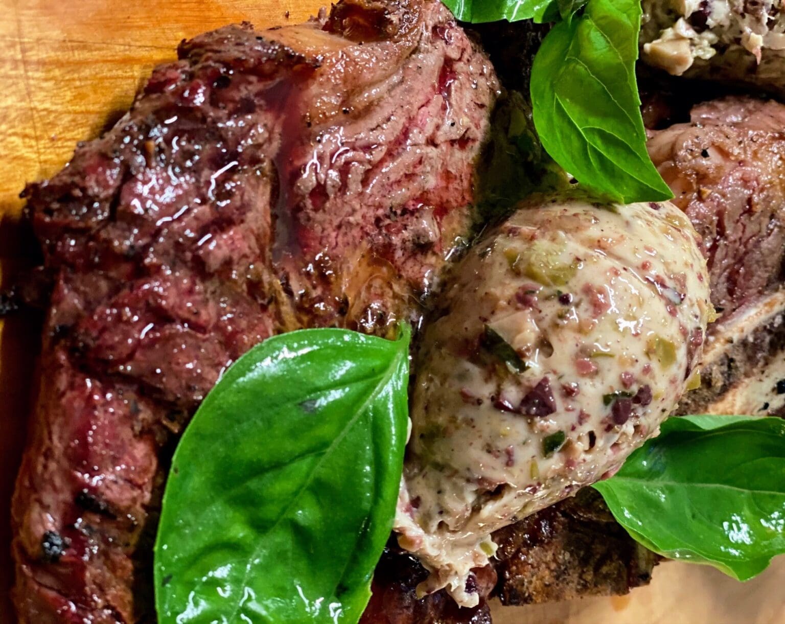Grass fed ribeye steak served with basil and tapenade butter.