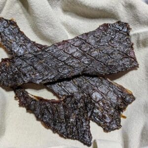 Grass Fed Beef Jerky from Wrong Direction Farm photographed on a linen cloth in a basket.