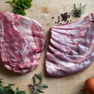 Grass fed lamb spare ribs on a cutting board with seasoning herbs.